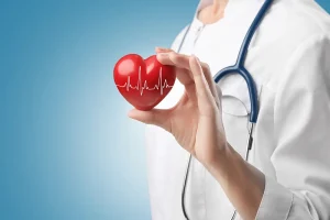 Cardiolog ținând în mână o inimă roșie cu electrocardiogramă. Poză reprezentativă de cardiologie, EKG.