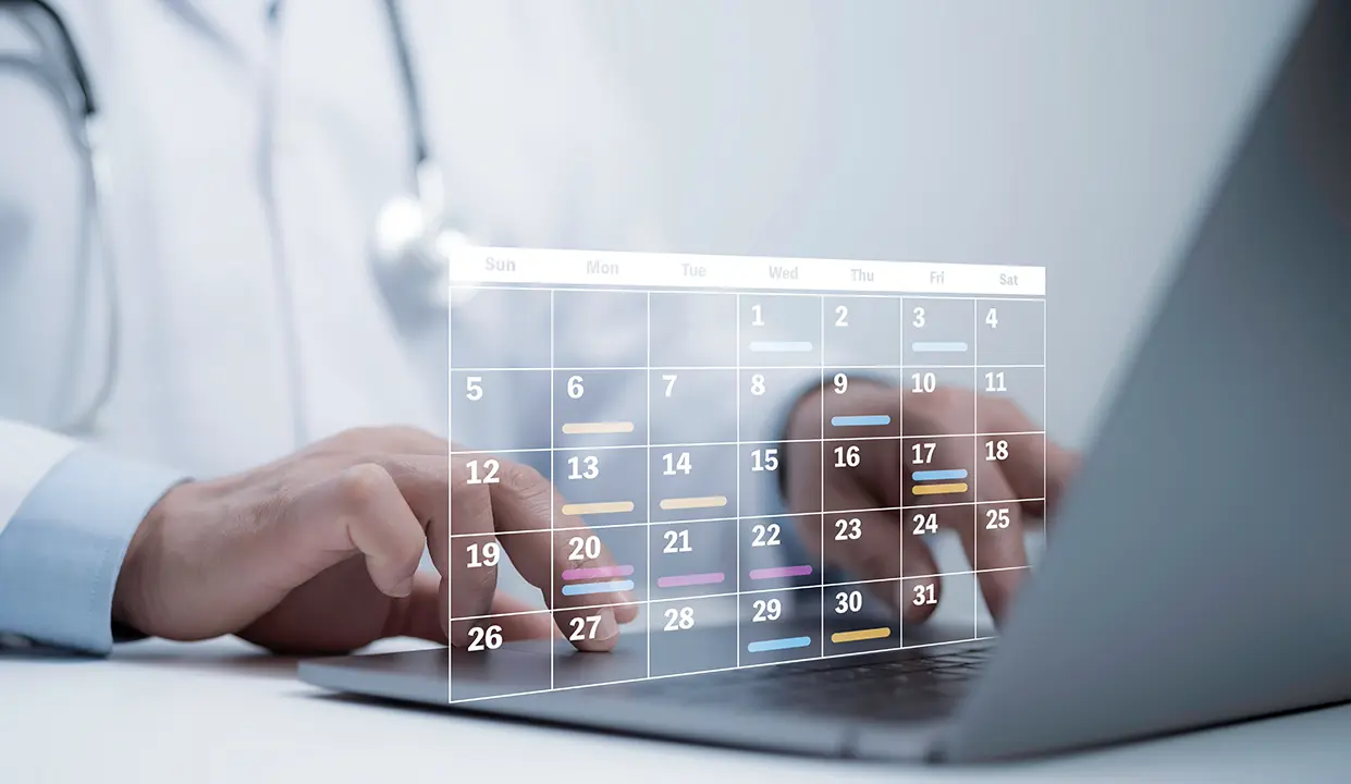 Poza reprezentativa pentru pagina cu programari a clinicii VenArt. Poza prezinta un calendar digital si mainile asistentului de la receptie care face o programare.